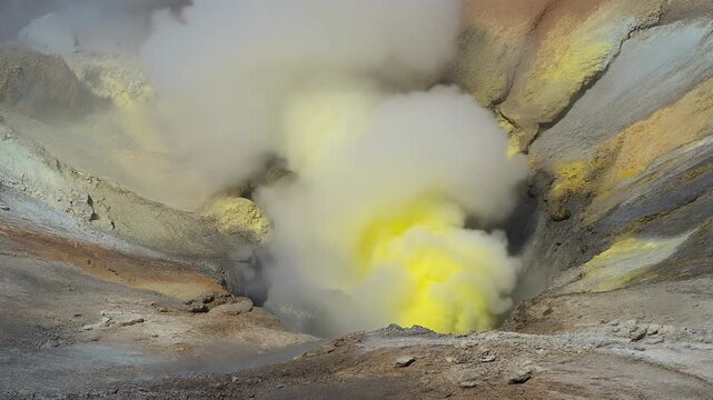 Yellow sulfurous gas and steam rising from a volcanic vent in a crater.