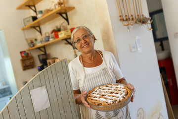 Senior woman holding homemade apple pie smiling