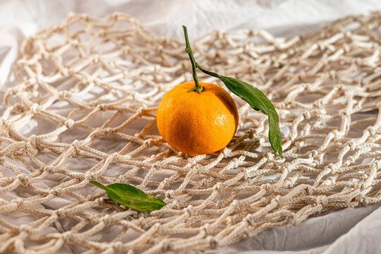 Fresh tangerine on woven fabric with green leaves