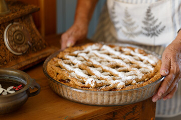 Hands holding freshly baked homemade apple pie with lattice crust