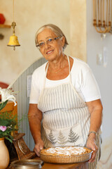 Smiling elderly woman baking homemade apple pie
