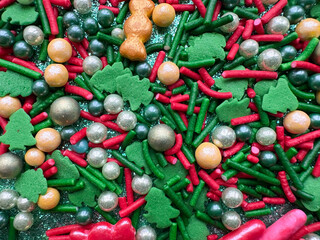 Christmas New Year wallpaper. Green, red and gold colored sugar sprinkles in the shape of Christmas trees and candy balls