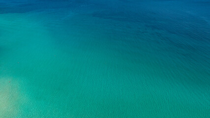 Obraz premium Aerial view of the crystalline sea surface. The water's colors range from blue to turquoise. Ideal for backgrounds, patterns, and textures of dreamy seas.