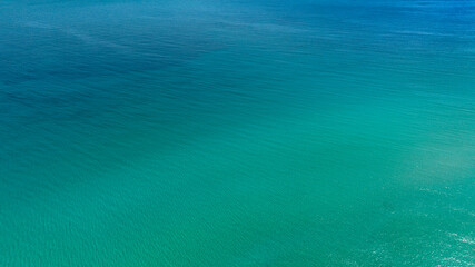 Aerial view of the crystalline sea surface. The water's colors range from blue to turquoise. Ideal for backgrounds, patterns, and textures of dreamy seas.