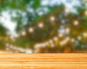 Wooden table surface with blurred background featuring green foliage and string lights perfect for product display or outdoor event promotion on transparent background