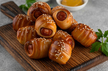 Mini hot dog bites with mustard and ketchup. Sausages baked in a yeast dough cover. Pigs in a...
