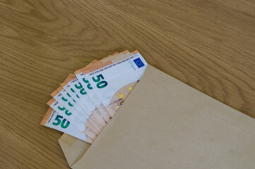 Fanned stack of 50 Euro notes peeking out from a brown manila envelope, implying a secret delivery of money