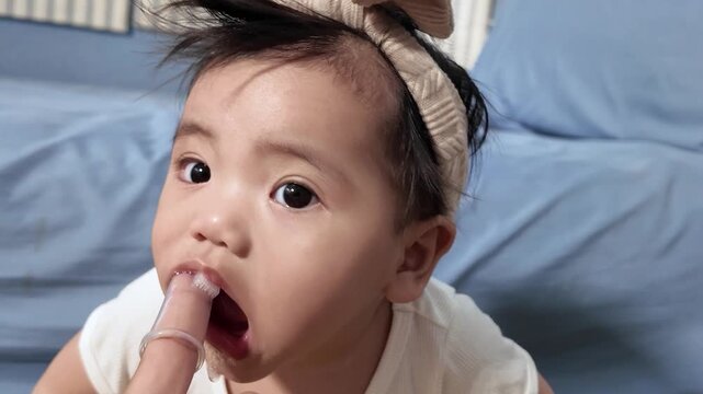 A mother gently brushing her baby's gums with a silicone brush to soothe pain and clean