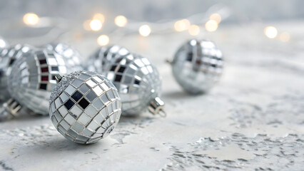 Silver disco balls on a white surface with bokeh lights in background