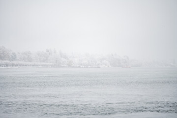 It is snowing on the snow-covered winter promenade along the waterfront in Petershausen. Constance,...