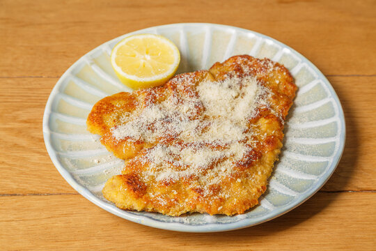 Escalope milanaise avec parmesan et citron sur une table en bois. Plat italien.