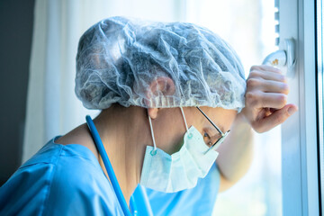 Close up an exhausted female medical professional in uniform thinks deeply about patient care plan, showing the difficult work of hospital staff.