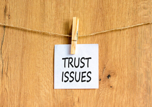 Trust issues symbol. Concept word Trust issues on beautiful white paper. Beautiful wooden clothespin. Beautiful wooden background. Business trust issues concept. Copy space.