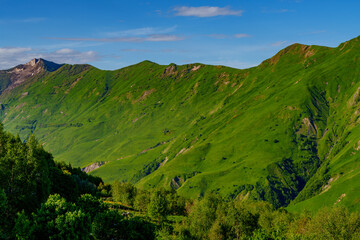 Sunlit green mountain ridge under clear blue late afternoon sky