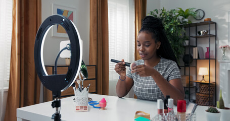 A beauty influencer opens a powder container, enjoys its fragrance, scoops it up with a large...