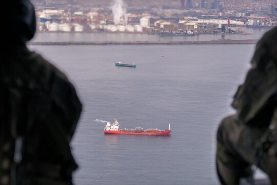 Aerial view of a cargo ship sailing on the water, with industrial buildings visible in the background, capturing a mix of maritime activity and urban landscape., Barcelona, Catalonia, Spain.