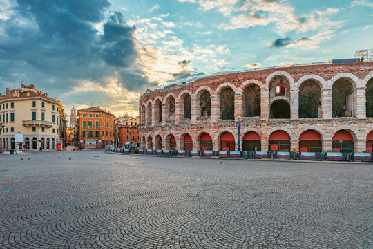 Ancient Roman amphitheater Arena di Verona at sunrise with colorful buildings and empty cobblestone Piazza Bra square, Verona old town, Veneto, Italy. Italian travel and touristic landmark