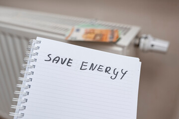 Handwritten note with the phrase 'SAVE ENERGY' on a notepad, positioned in the foreground. A...