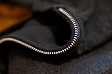 Close-up of a zipper on a black fabric showcasing intricate details. This image captures the texture and design of clothing materials, suitable for fashion contexts.