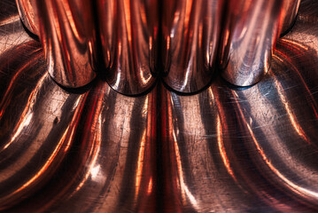 Copper rods on a convex metal surface, forming abstract curves, a concept of the fluidity of non-ferrous metals