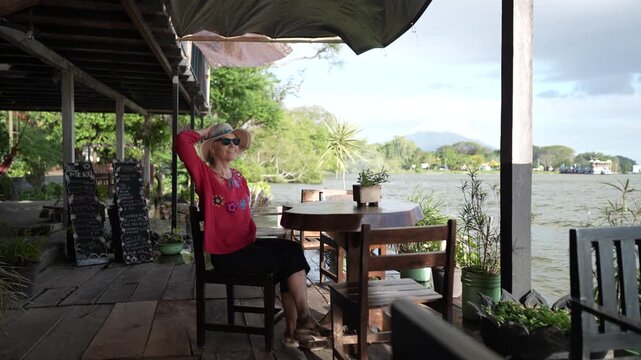 A mature woman relaxes by the water on Ometepe Island, appreciating the stunning views of Madeira Volcano and the serene surroundings.