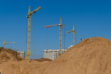 Several tower cranes stand tall over a large new high-rise residential development