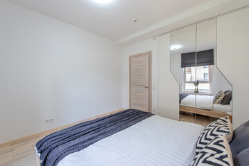 Modern Minimalist Bedroom Interior with Large Mirror and Stylish Bedding
