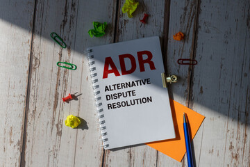 ADR Alternative Dispute Resolution is written in a white notepad near a calculator