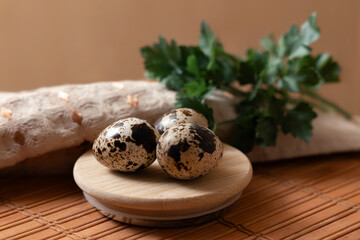 Three quail eggs on a round wooden plate placed on a wooden surface with a linen napkin. Concept of natural nutrition, organic food, eco products, rustic cooking and healthy lifestyle.