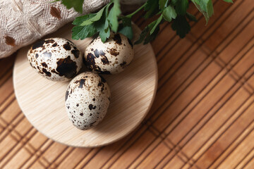 Three quail eggs on a round wooden plate placed on a wooden surface with a linen napkin. Concept of natural nutrition, organic food, eco products, rustic cooking and healthy lifestyle.