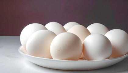 Fototapeta premium White eggs arranged neatly in a white dish, sitting on a white surface with a muted, dark gradient background