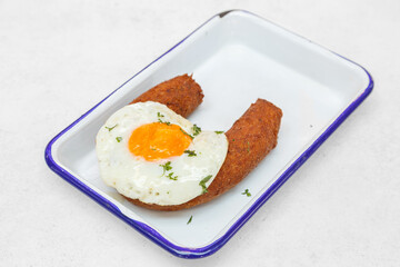 Alheira frite avec œuf au plat – saucisse portugaise sur une table en bois. Cuisine portugaise. 