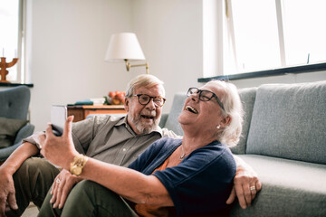 Senior couple laughing joyfully on video call at home