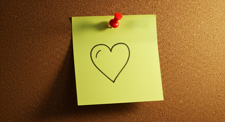Yellow sticky note with heart drawing pinned to a corkboard  