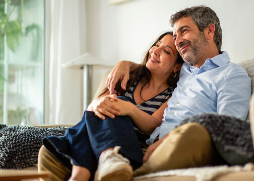 Loving couple cuddling and smiling together while relaxing on couch at home
