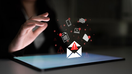 A hand reaches towards a digital tablet displaying an email icon with a warning sign, surrounded by various communication symbols, depicting urgency and security concerns. Gantry