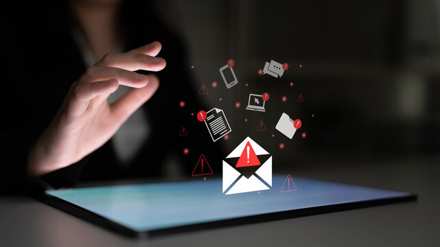 A hand reaches towards a digital tablet displaying an email icon with a warning sign, surrounded by various communication symbols, depicting urgency and security concerns. Gantry