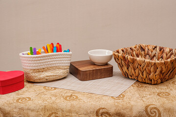 Rustic arrangement featuring woven baskets, a wooden riser and colorful craft sticks against a neutral backdrop. Creating a versatile aesthetic for product display. Perfect for e-commerce promotion.