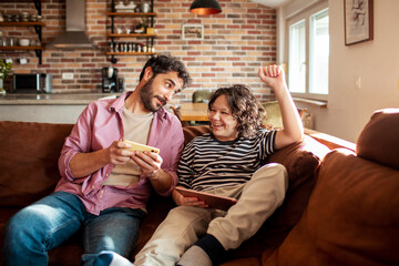 Adult father and child son laughing with digital devices at home