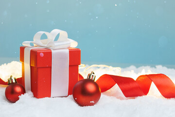 Gift box on snow with two baubles, copy space