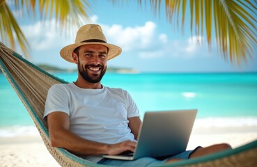 Smiling man in straw hat works on laptop, relaxing in comfortable hammock. Enjoys beautiful tropical beach view with clear blue ocean, white sand, rich palm trees. Digital nomad lifestyle offers