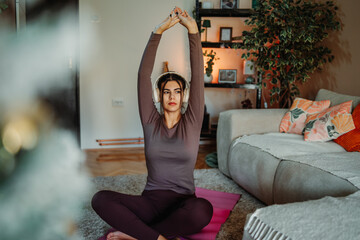 Obraz premium Woman practicing yoga with headphones at home