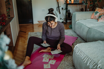 Obraz premium Woman choosing home yoga workout routine cards