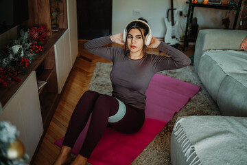 Woman exercising home workout with resistance band and headphones