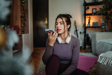 Woman recording voice message on smartphone at home