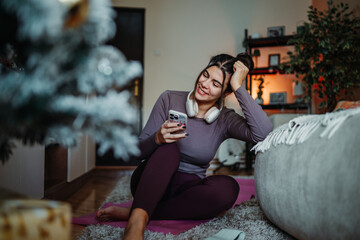 Obraz premium Woman relaxing at home, enjoying music and smartphone during holiday season