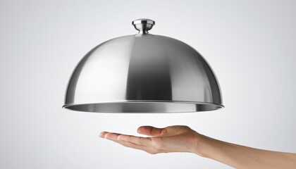 Hand holding floating stainless steel cloche against minimalistic background