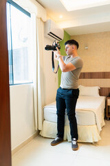Young man taking a photo on his reflex camera at the window.