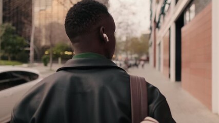 Back view of the Young Man Walking Down City Street