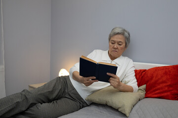 Mature Asian woman reading a book in the room